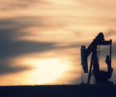 A pumpjack at an oil drilling site at sunset.